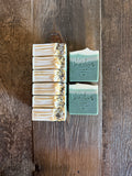 Green and white soaps with tea leaves on top.