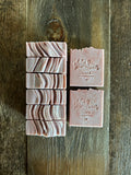 Image shows a group of soft pink and purple hued soap with glitter on top.