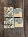 Green and white soaps with yellow petals and salts on top.